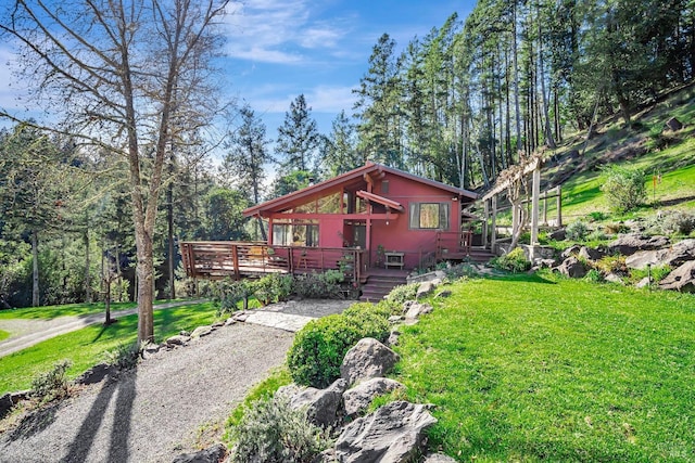 chalet / cabin featuring a wooden deck and a front lawn