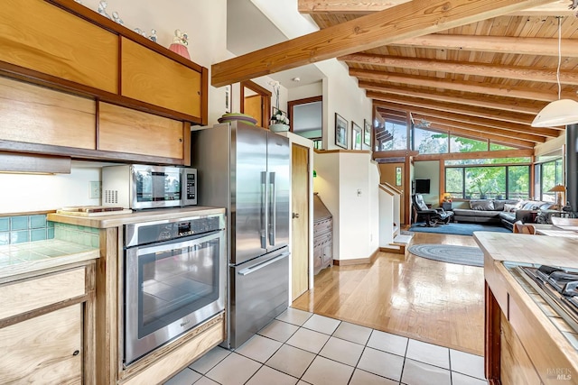 kitchen with light tile patterned floors, wood ceiling, beam ceiling, stainless steel appliances, and high vaulted ceiling