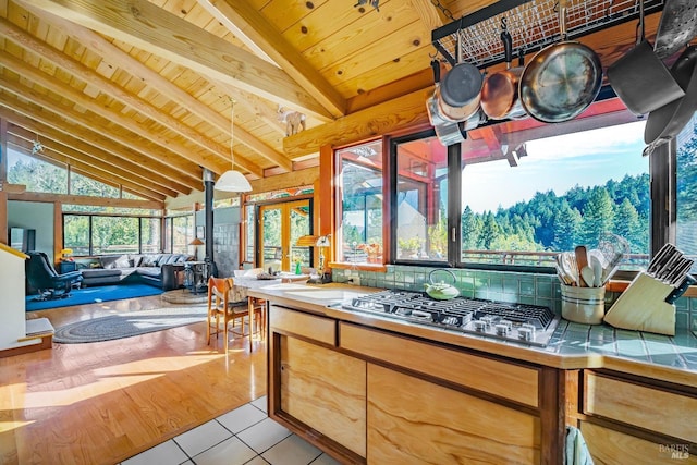 kitchen with lofted ceiling with beams, light tile patterned floors, wood ceiling, tile counters, and stainless steel gas cooktop