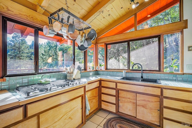 kitchen with sink, wood ceiling, light tile patterned floors, tile counters, and decorative backsplash