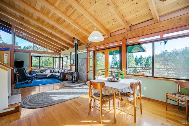 sunroom with lofted ceiling with beams, wood ceiling, a wood stove, and french doors