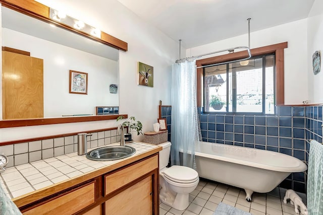 full bathroom with tile walls, vanity, toilet, shower / bathtub combination with curtain, and tile patterned floors