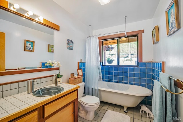 full bathroom featuring tile walls, vanity, tile patterned floors, toilet, and shower / bath combo with shower curtain