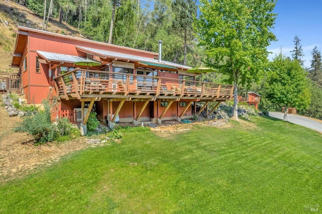 back of house featuring a deck, a lawn, and metal roof