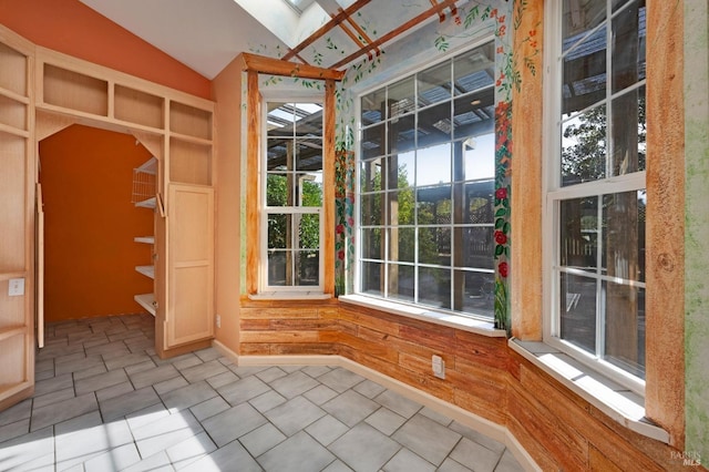 interior space with lofted ceiling with skylight and light tile patterned flooring