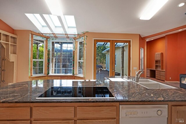 kitchen with black electric stovetop, white dishwasher, french doors, dark stone counters, and sink