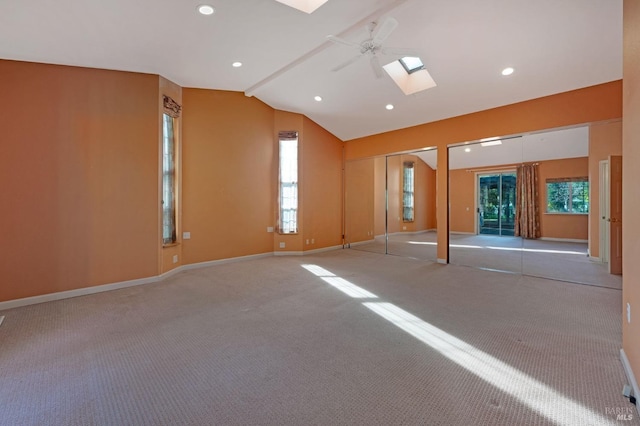 carpeted spare room with ceiling fan, plenty of natural light, and lofted ceiling with skylight