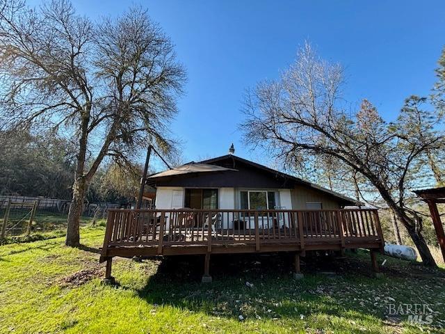 back of property featuring a wooden deck and a yard