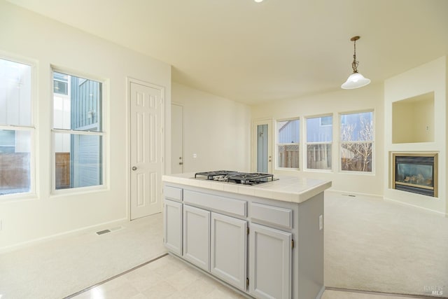 kitchen featuring decorative light fixtures, light colored carpet, a wealth of natural light, and tile countertops