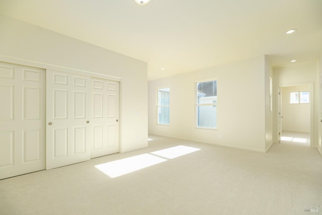 unfurnished bedroom with light carpet and a closet