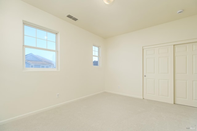 unfurnished bedroom featuring light carpet and a closet