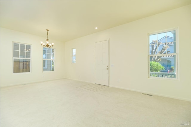 spare room with carpet and an inviting chandelier