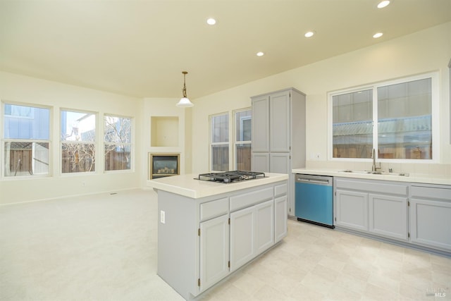 kitchen with pendant lighting, appliances with stainless steel finishes, a center island, light carpet, and sink