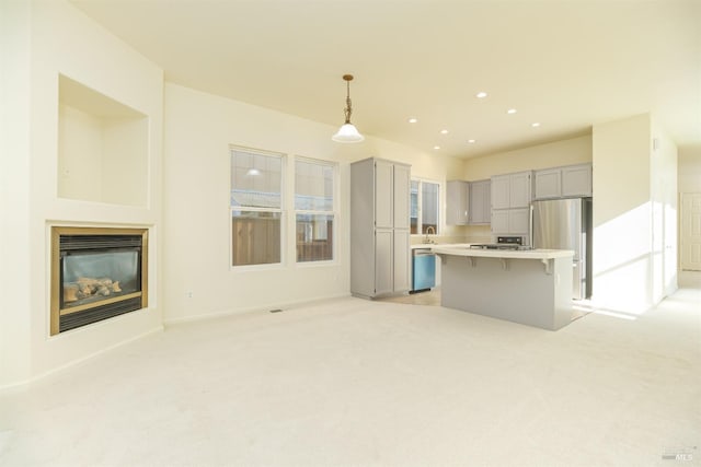 kitchen featuring pendant lighting, a center island, gray cabinets, stainless steel refrigerator, and a breakfast bar area