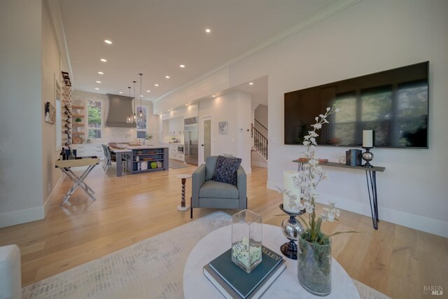 living room with a wealth of natural light, light hardwood / wood-style floors, and ornamental molding