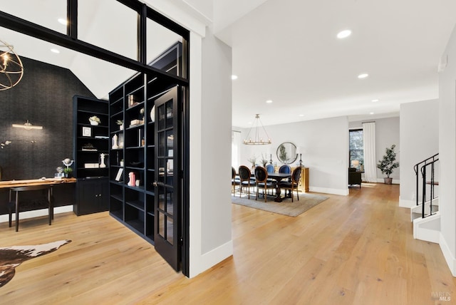 wine room with hardwood / wood-style floors, built in features, lofted ceiling, and a notable chandelier