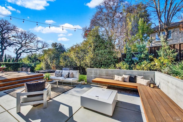 view of patio with a wooden deck and an outdoor living space with a fire pit