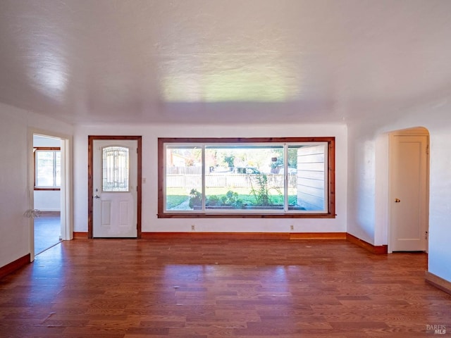 unfurnished living room featuring a healthy amount of sunlight and dark wood-type flooring