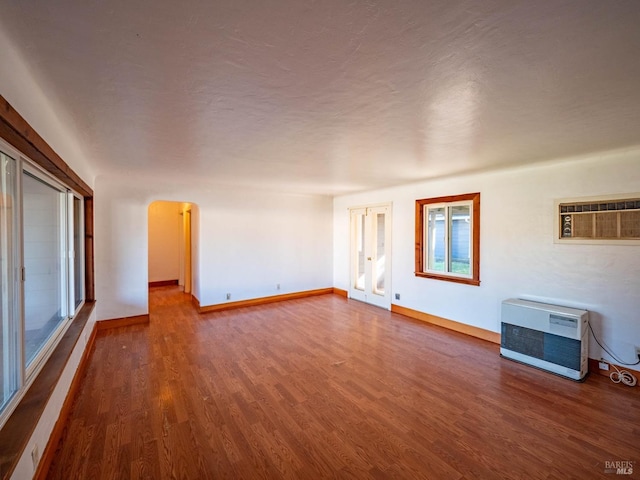 unfurnished living room with hardwood / wood-style flooring, plenty of natural light, heating unit, and a wall mounted AC