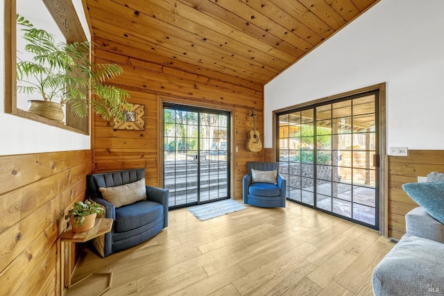 sitting room featuring wood ceiling, lofted ceiling, light hardwood / wood-style floors, and wood walls