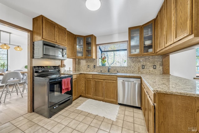 kitchen featuring light tile patterned floors, appliances with stainless steel finishes, backsplash, light stone countertops, and sink