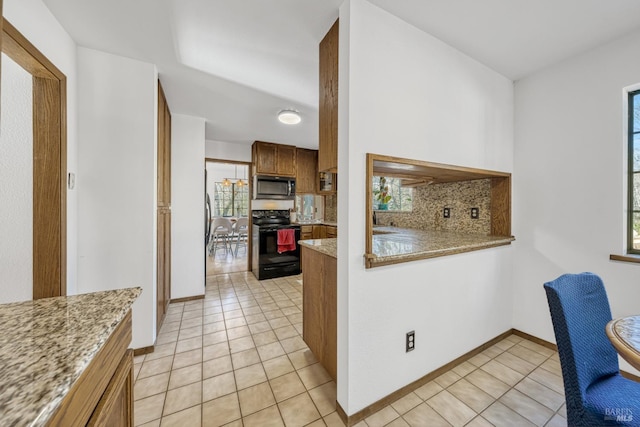 kitchen with light tile patterned floors, decorative backsplash, black electric range oven, and light stone countertops