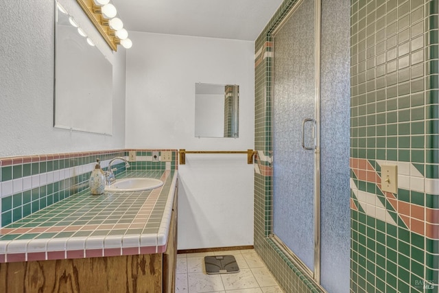 bathroom with a shower with door, tile patterned floors, and vanity