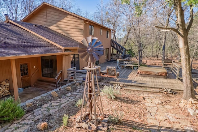 rear view of property featuring a wooden deck and a jacuzzi