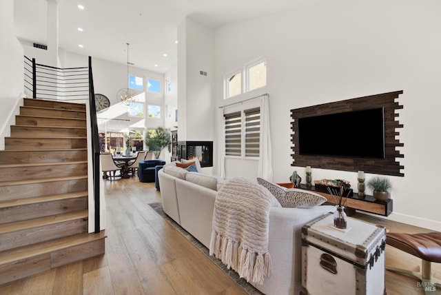 living room with a notable chandelier, light hardwood / wood-style flooring, and a high ceiling