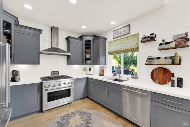 kitchen featuring gray cabinets, wall chimney exhaust hood, and appliances with stainless steel finishes