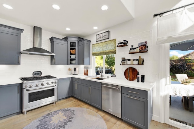 kitchen featuring gray cabinets, appliances with stainless steel finishes, sink, and wall chimney range hood