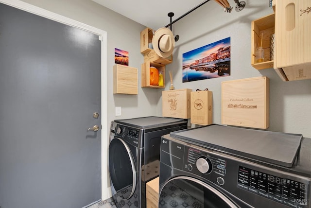 clothes washing area featuring washer and clothes dryer and cabinets