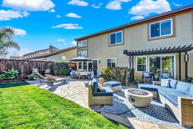 back of house with a lawn, a patio, and an outdoor living space with a fire pit