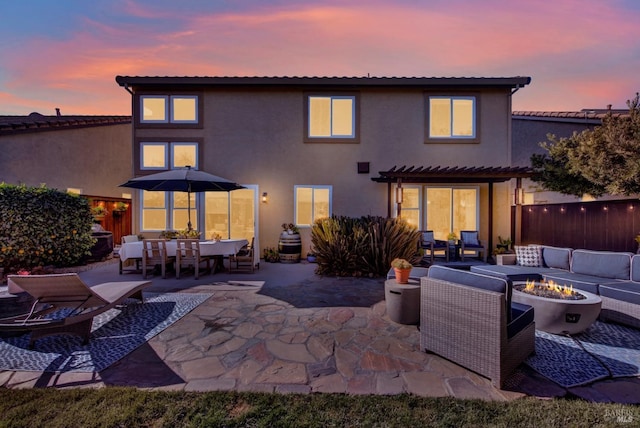 back house at dusk with an outdoor living space with a fire pit, a patio area, and a pergola