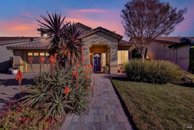 mediterranean / spanish house featuring a garage and a lawn