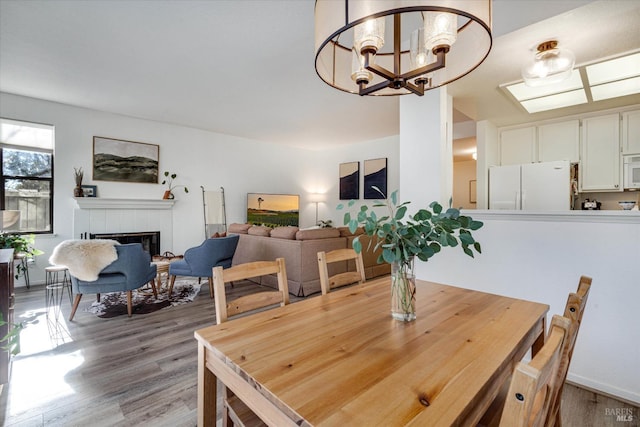 dining room with a chandelier, light hardwood / wood-style flooring, and a tiled fireplace