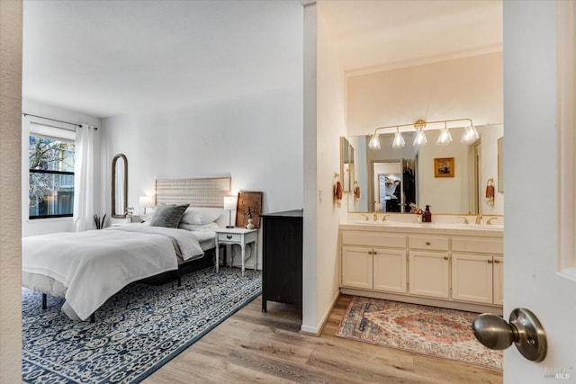 bedroom with light hardwood / wood-style floors, sink, and connected bathroom