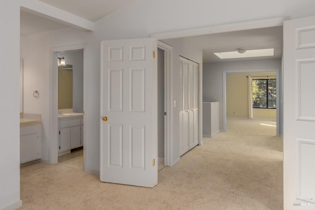 hallway featuring vaulted ceiling, light colored carpet, and sink