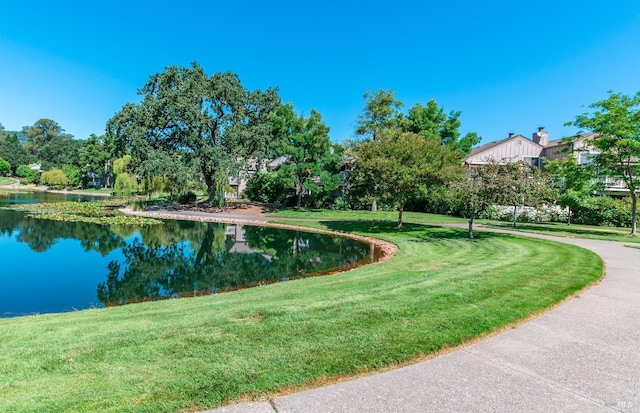 view of home's community with a water view and a lawn