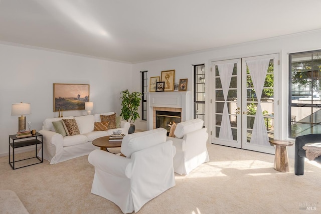 carpeted living room with ornamental molding, french doors, and a tile fireplace