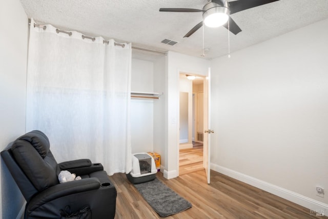 sitting room featuring ceiling fan, a textured ceiling, and hardwood / wood-style floors