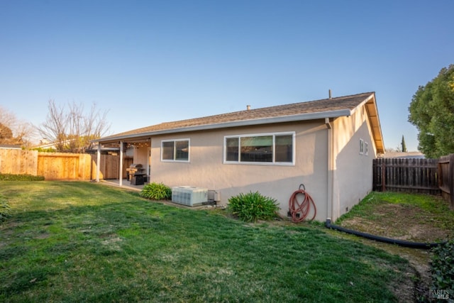 rear view of property with central air condition unit, a patio, and a yard