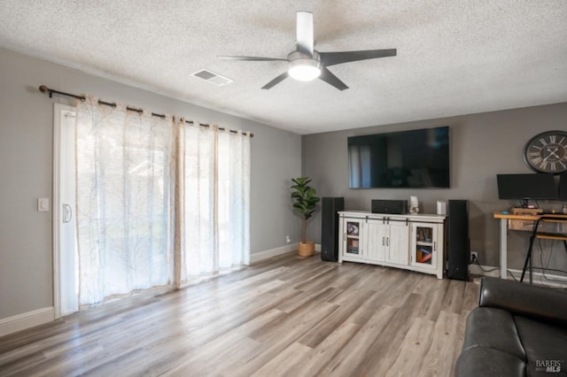 living room with ceiling fan, a textured ceiling, and light hardwood / wood-style floors