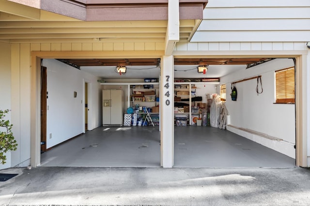 garage featuring a garage door opener and white fridge with ice dispenser