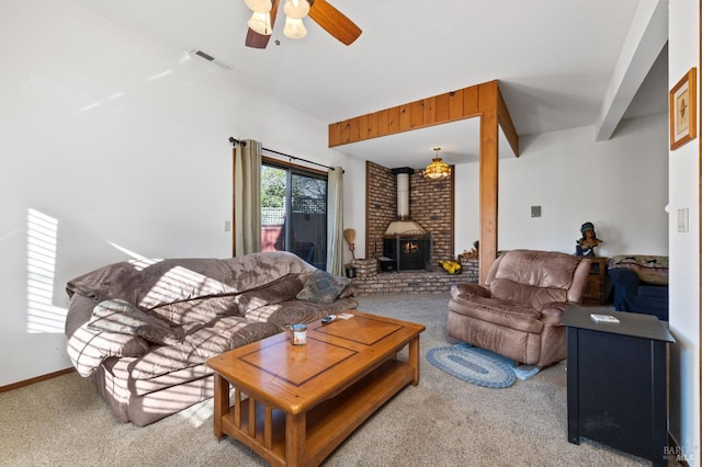 living room featuring ceiling fan, a wood stove, carpet, and beamed ceiling