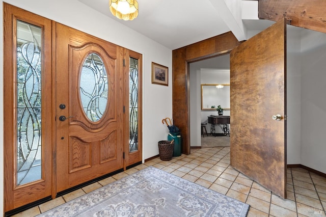 entrance foyer featuring light tile patterned floors and beamed ceiling