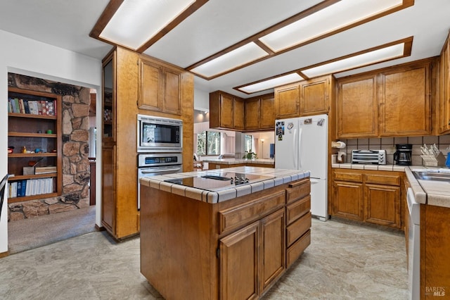 kitchen featuring appliances with stainless steel finishes, sink, tasteful backsplash, a center island, and tile counters