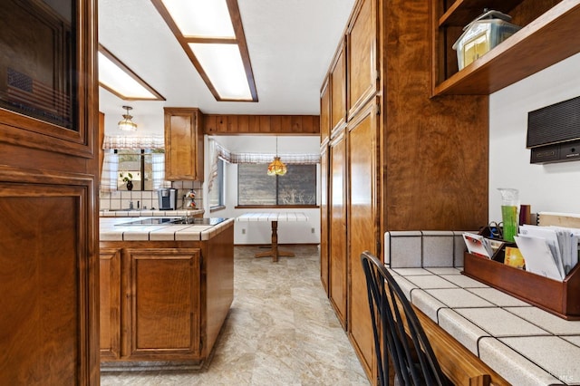 kitchen featuring decorative light fixtures, black electric stovetop, and tile counters