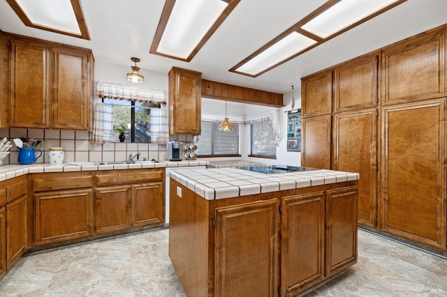 kitchen with a center island, tasteful backsplash, hanging light fixtures, tile countertops, and black electric cooktop