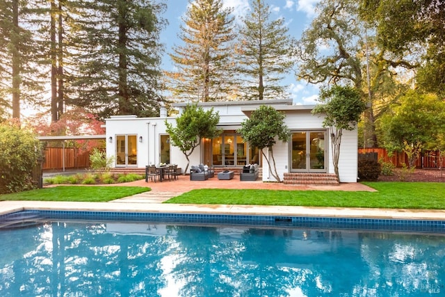 back of house featuring an outbuilding, a lawn, outdoor lounge area, and a patio